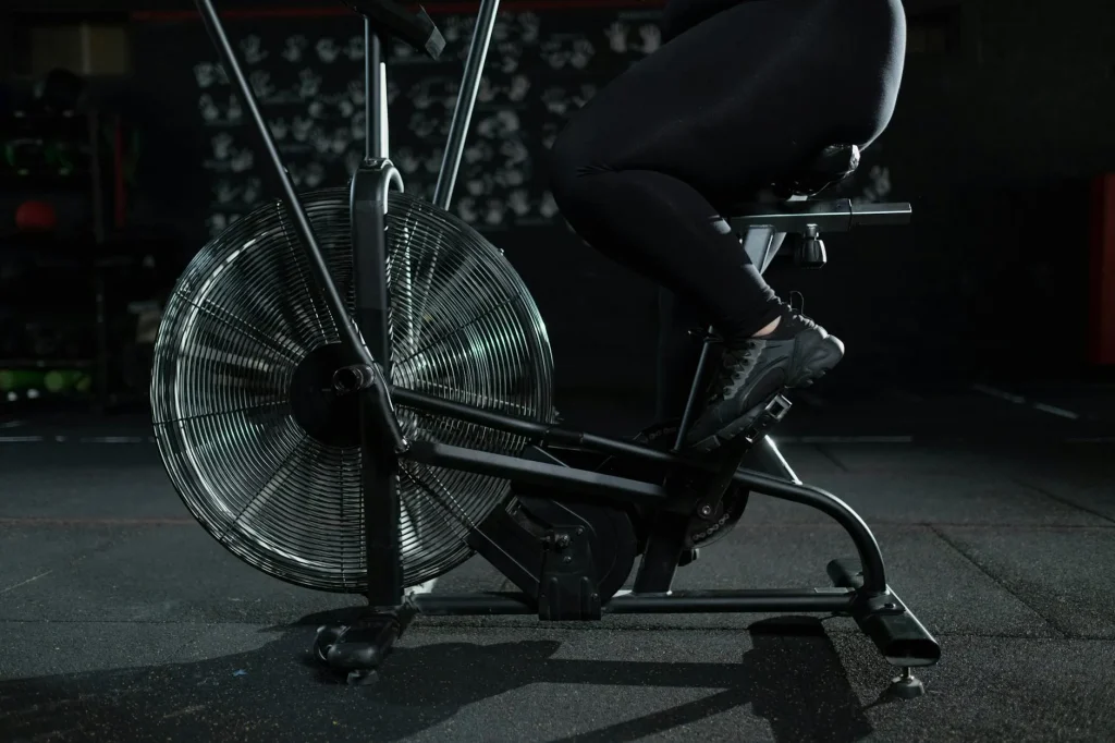 Person using an air bike for a HIIT workout in a home gym