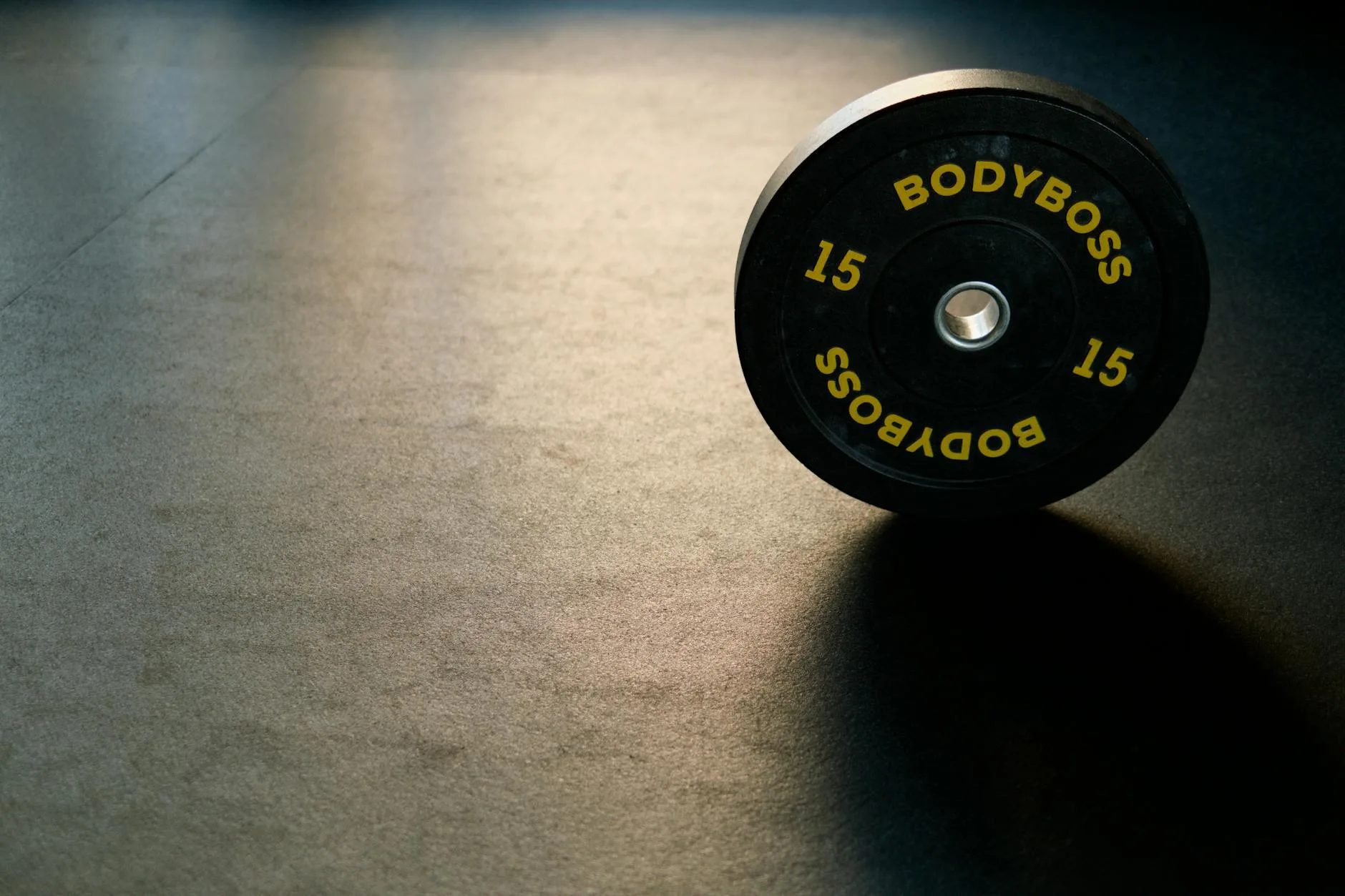 Bumper plate resting on rubber gym flooring in a home gym