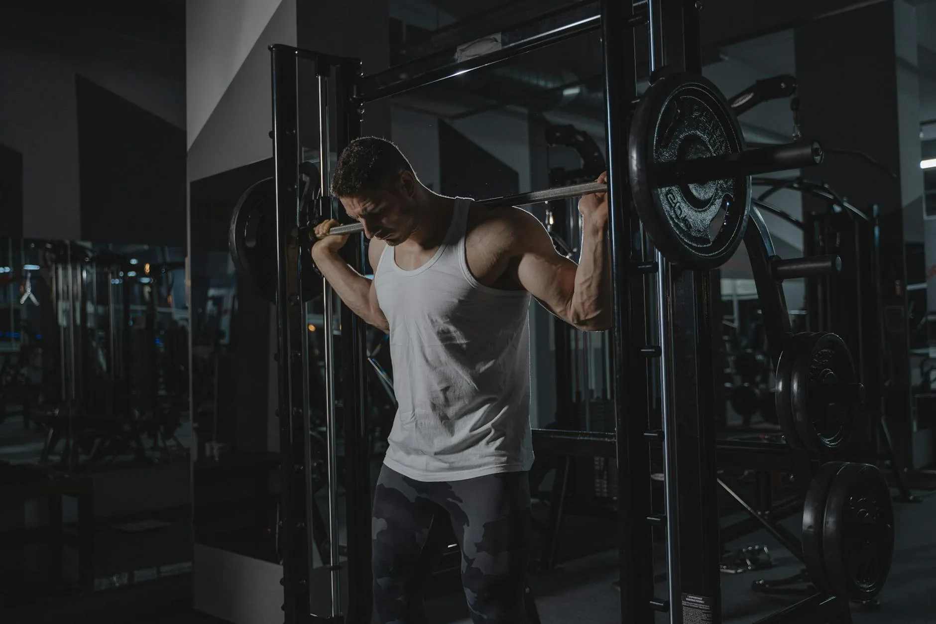 Man squatting heavy barbell in a squat rack at the gym