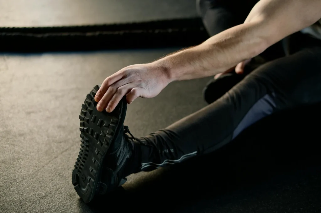 Person performing dynamic warm-up stretches in a gym before weightlifting workout
