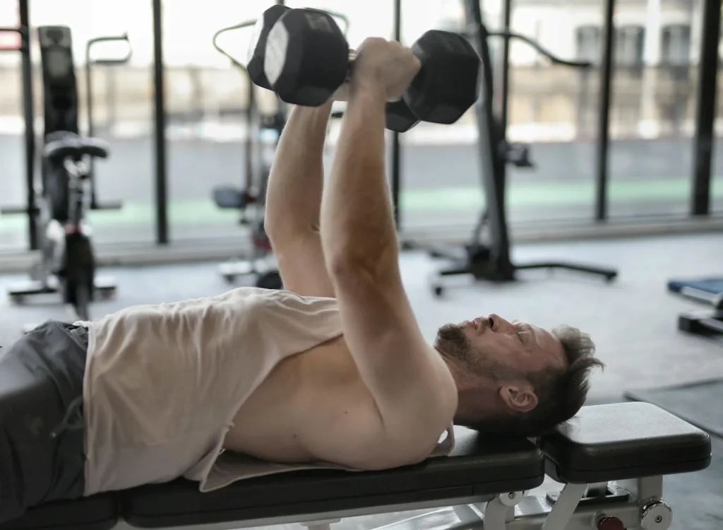 Person doing dumbbell press on an adjustable weight bench in a home gym