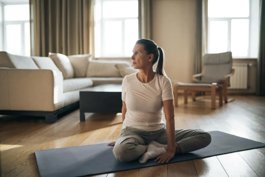 Person stretching on yoga mat in a bright living room for home recovery