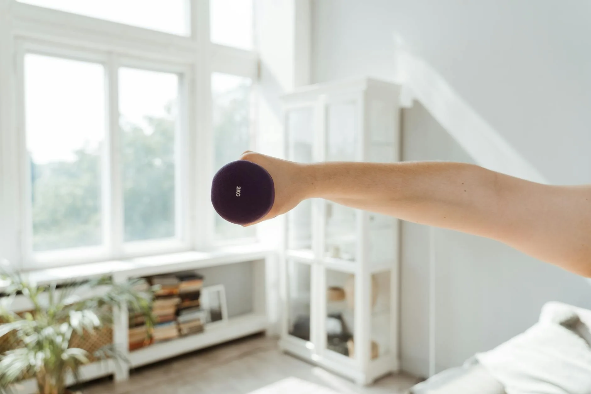Person exercising with dumbbells in a small home gym