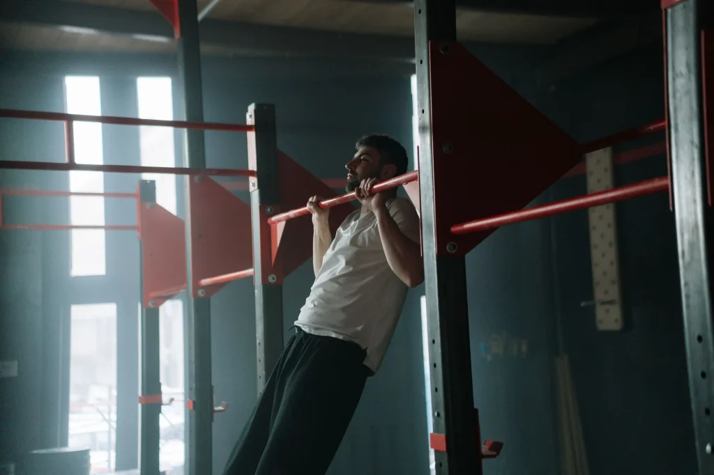 Beginner practising pull up progressions on a gym pull up bar